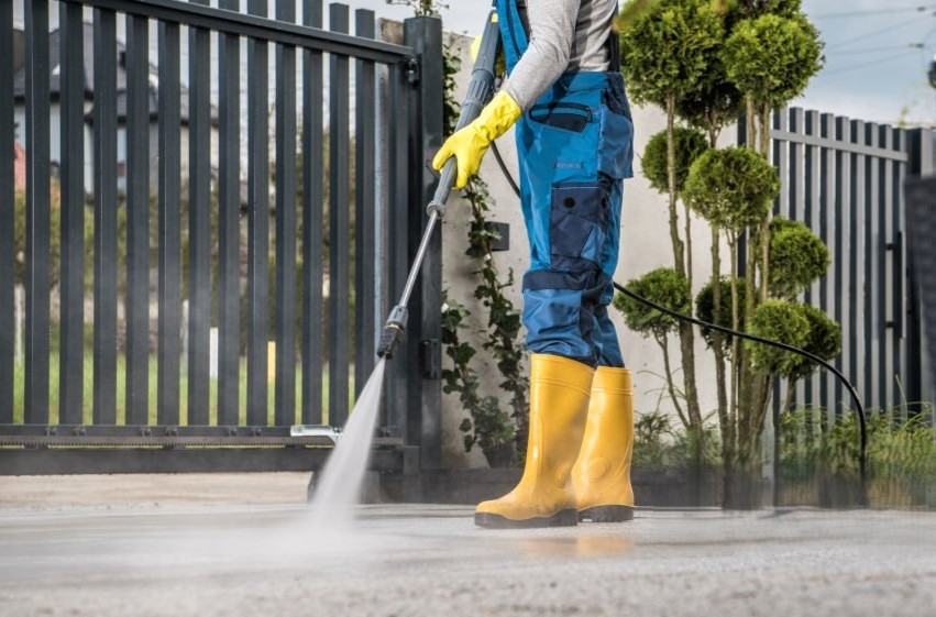 High-pressure washer cleaning a paved outdoor driveway